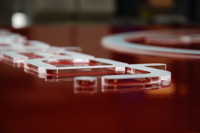 Close-up view of a red totem sign showing protruding illuminated sign lettering.